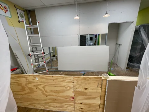 División revestida con una abertura horizontal y mostrador en construcción, con tablero de madera visible en el frente.