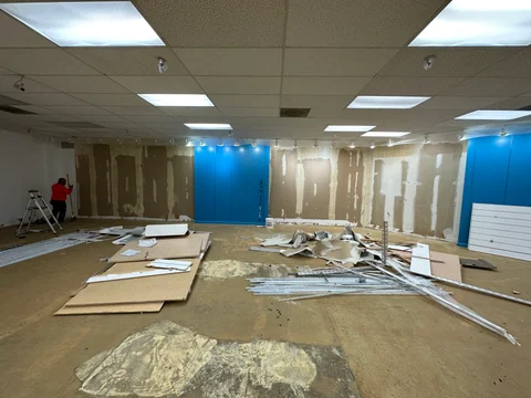 The main room during the work, with exposed wall sections and removed finishes on the floor.
