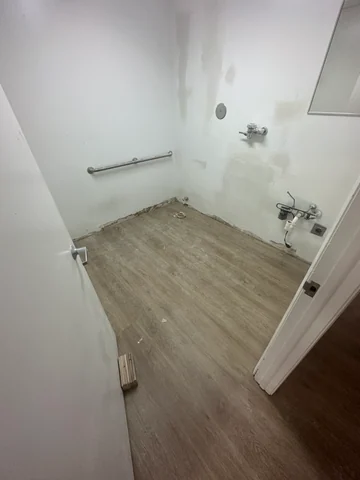Bathroom during renovation, with walls being prepared, exposed connections and flooring in place.