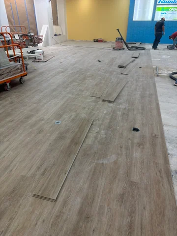 View along the main room with flooring partly installed, loose pieces and work areas still visible.