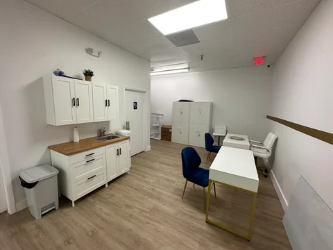 Support area with white cabinets, a sink, a table and chairs beside the passage to other rooms.