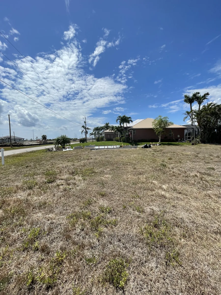 Lote de Cape Coral antes de levantar la casa, con césped y viviendas vecinas.