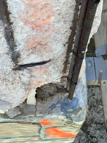 Close view of an opening in the exterior wall beside an exposed metal element and construction markings.