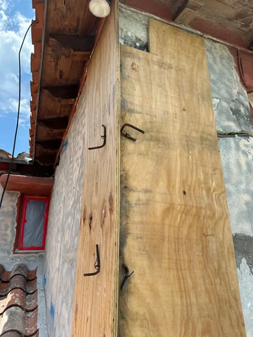 Wooden formwork on an exterior corner, with projecting steel bars and the house eaves above.