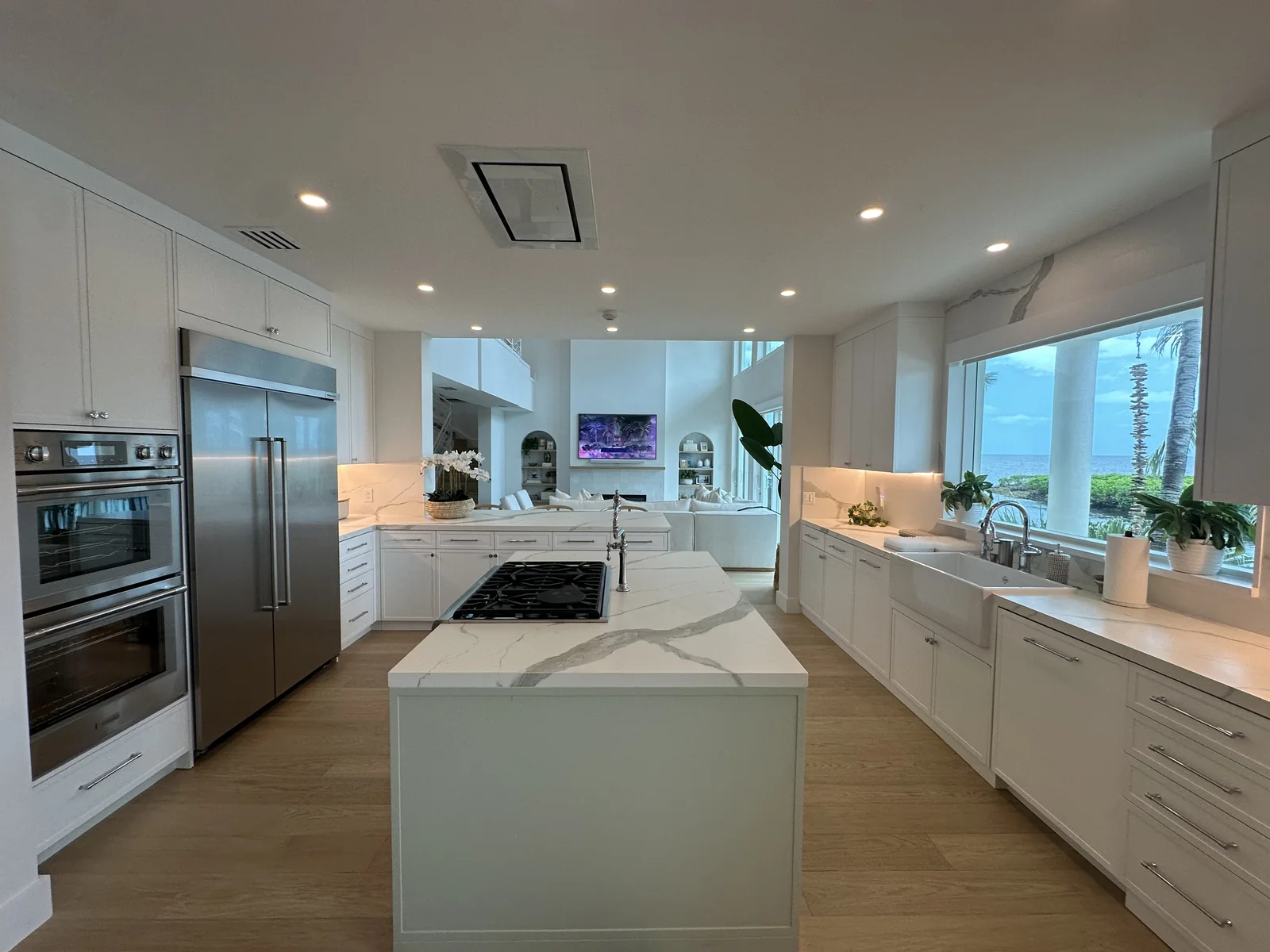 Cocina de Coral Gables con isla, muebles blancos y ventanas amplias.