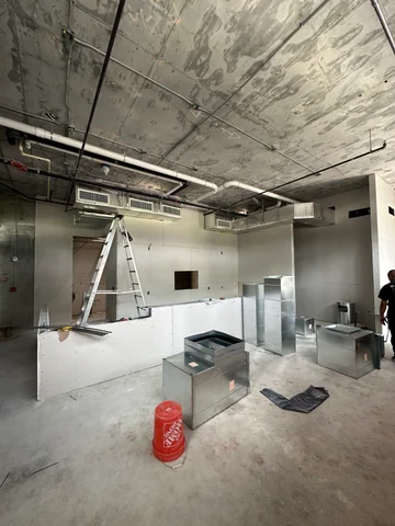 Bar area with drywall panels installed, joints being prepared and construction materials on the floor.