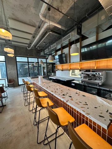 View along the Craft bar, with yellow stools, pendant lights and glazing toward the entrance.