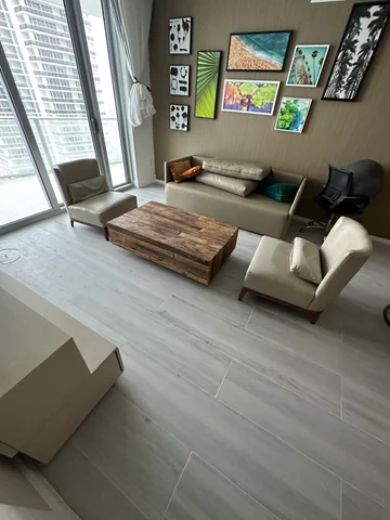 Living room with light plank-style flooring, a sofa, wood coffee table and glazing toward the balcony.