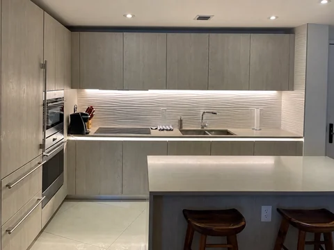 Gray kitchen with a peninsula, light countertop and under-cabinet lighting.