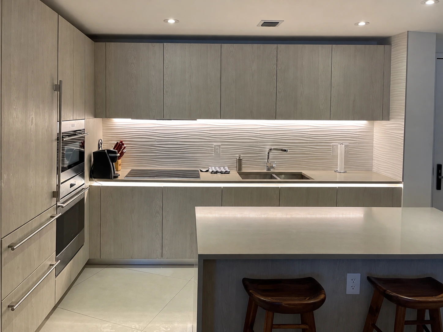 Gray kitchen with a peninsula, light countertop and under-cabinet lighting.