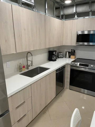 Kitchen with cabinets, countertop and appliances in place, with the upper framing and duct exposed.