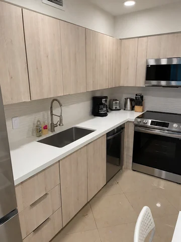 Kitchen with light-wood cabinets, a white countertop, stainless-steel appliances and a white ceiling.
