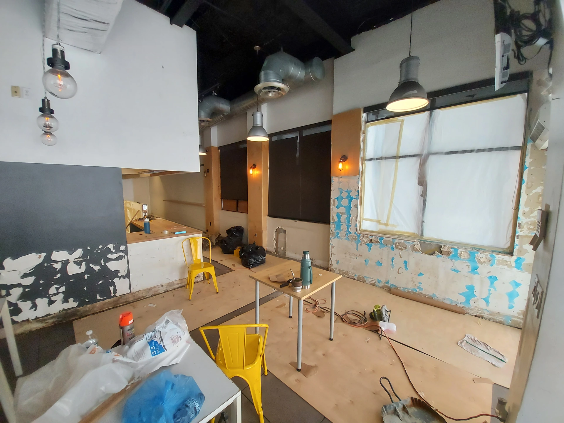 Interior de Smile Empanadas durante la obra, con paredes en preparación, ventanas protegidas y materiales sobre el piso.