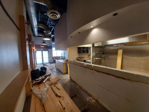 Vista a lo largo del mostrador de Smile Empanadas durante la obra, con la cocina a un lado y el acceso al fondo.