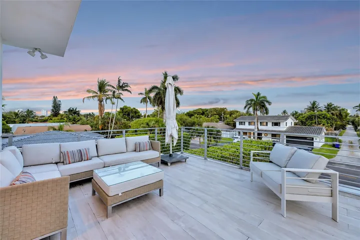 Washington’s open terrace at sunset, with light outdoor seating, a coffee table and views over palms and the neighborhood.