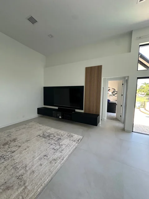 Weston Hills living area with a high ceiling, light walls, continuous flooring and windows facing the garden.